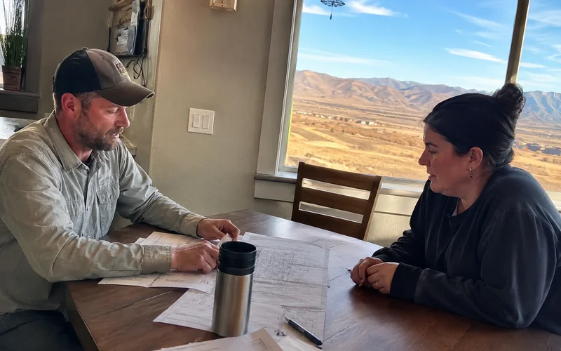 Landscaper reviewing an itemized bid with a homeowner at a kitchen table
