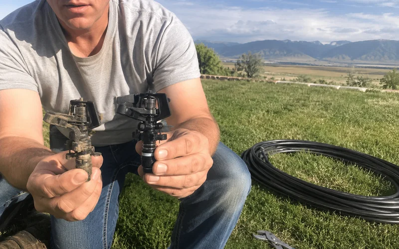 Technician comparing an old worn sprinkler head with a new replacement