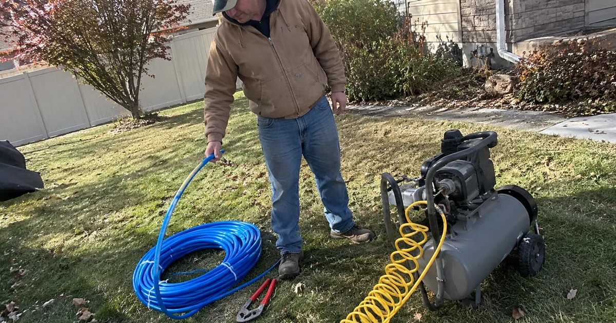 Compressor hooked up to a residential sprinkler system during a fall blowout