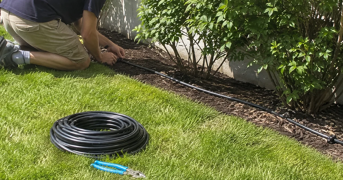 Drip tubing with emitters running at the base of shrubs in a mulched Utah garden bed