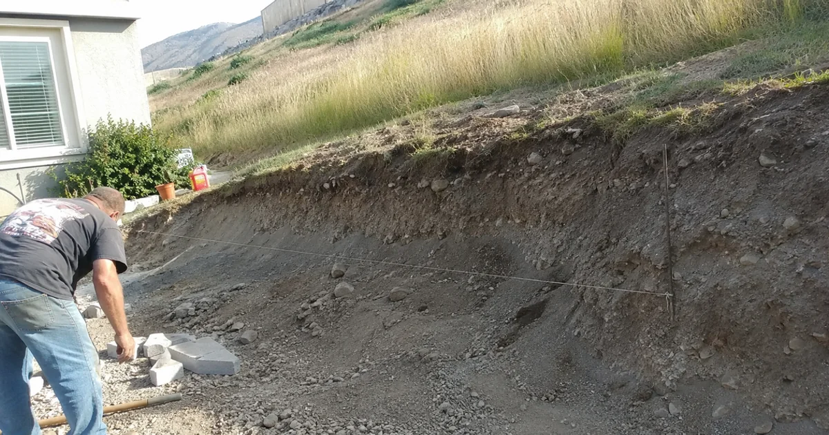 Eroding bare slope in a Utah back yard with washed-out soil at the base