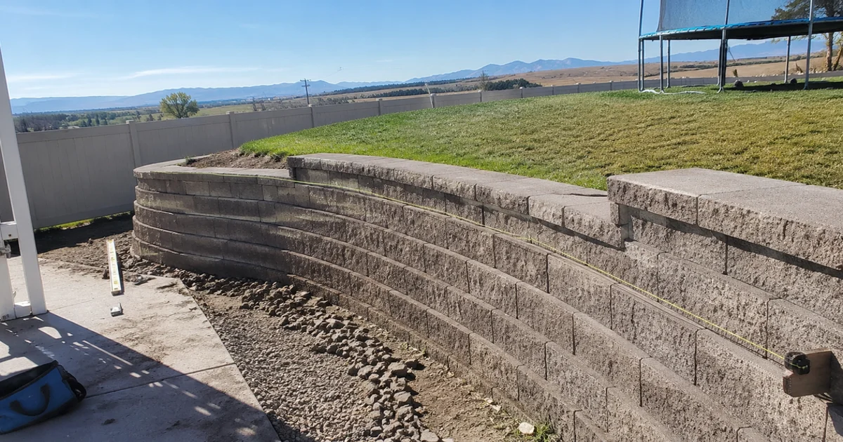 Finished segmental block retaining wall running across a Utah property with level lawn above