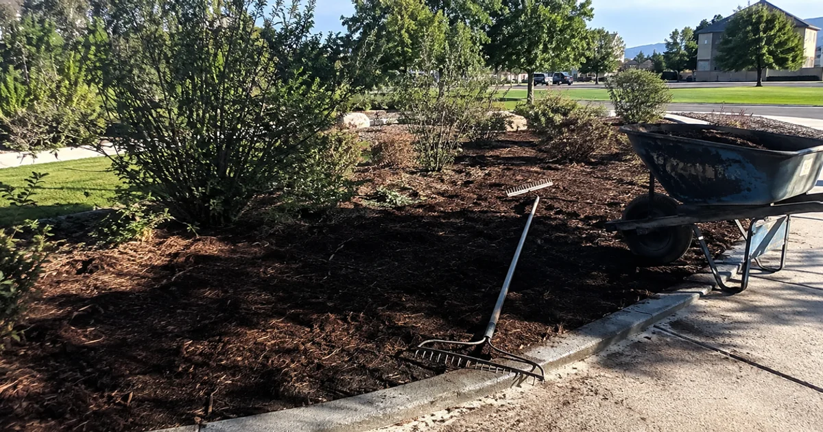 Fresh bark mulch spread evenly through a Utah landscape bed around established shrubs