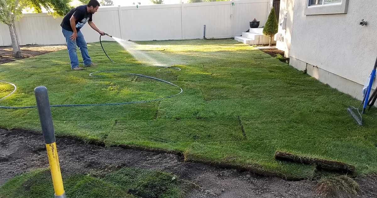 Freshly laid green sod lawn being watered in for the first time at a Utah home
