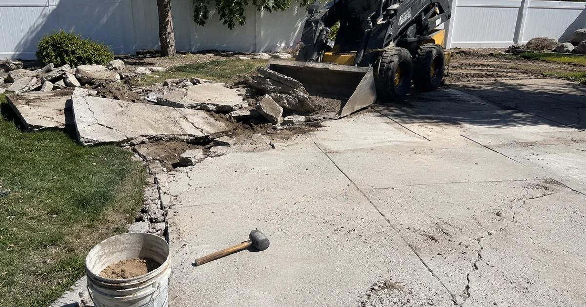 Old concrete patio being broken up and loaded for removal in a Utah back yard