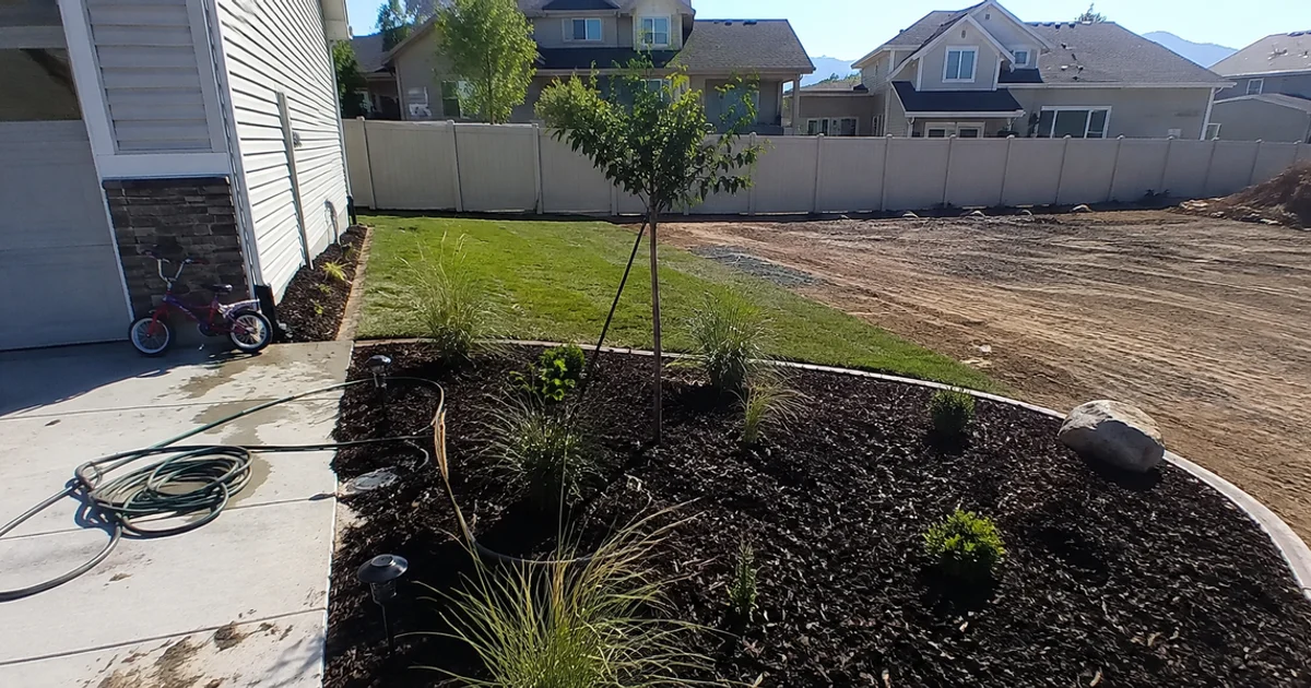 A partially landscaped Utah yard with one finished section and another still bare dirt
