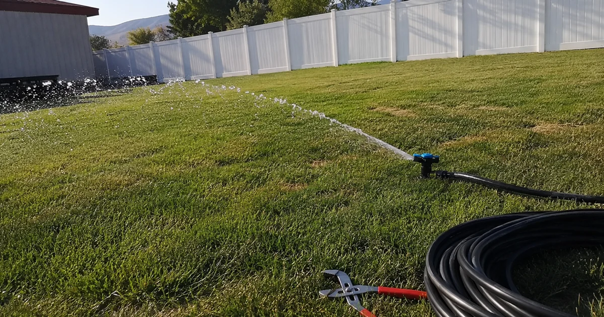 Sprinkler head throwing an even arc of water across a green Utah lawn