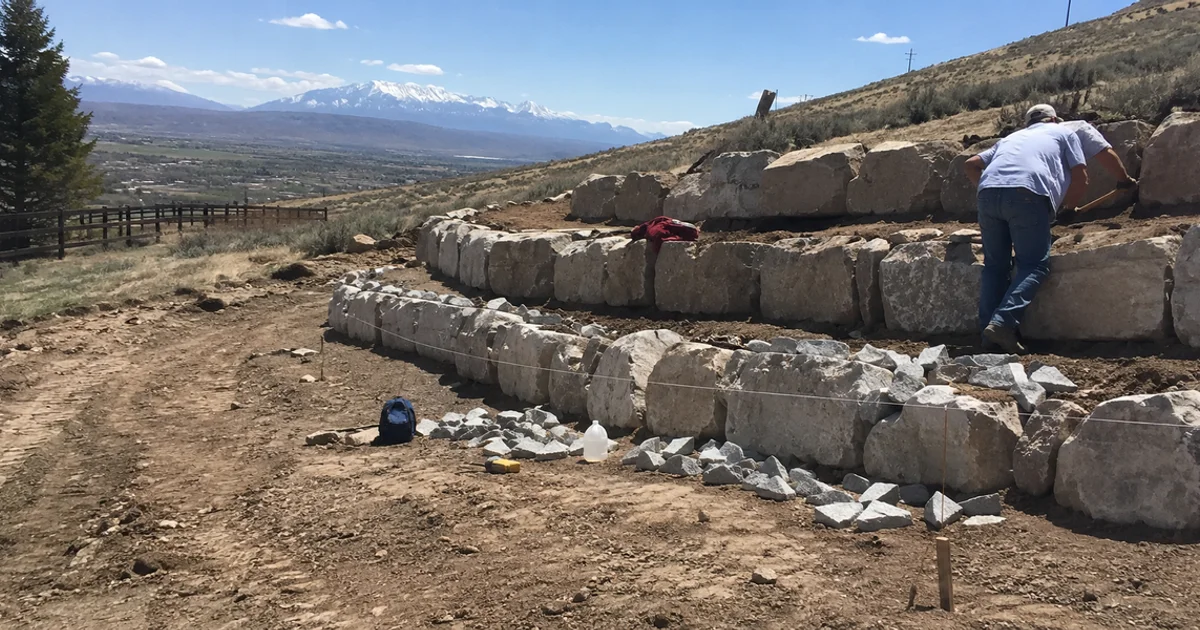 Terraced boulder retaining walls stepping down a sloped rural Utah lot