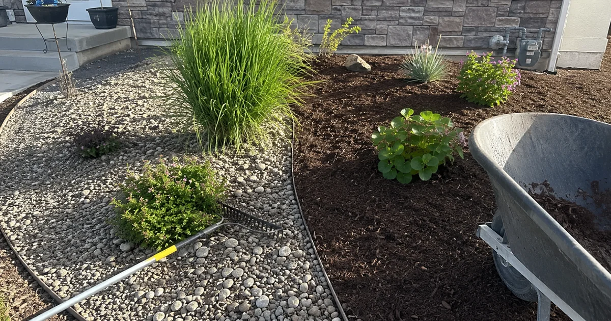 A Utah landscape bed split between decorative gravel and bark mulch around the same plants