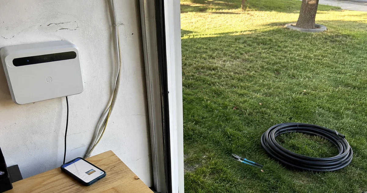 Wall-mounted smart WiFi sprinkler controller in a Utah garage with a phone showing the app