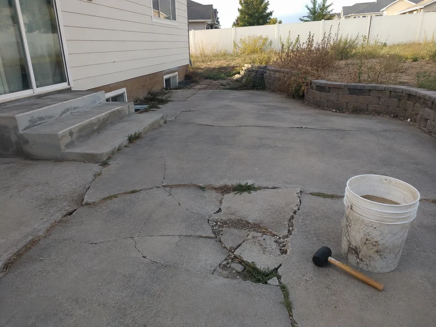 Cracked, failing concrete patio and tired old landscaping before demolition begins