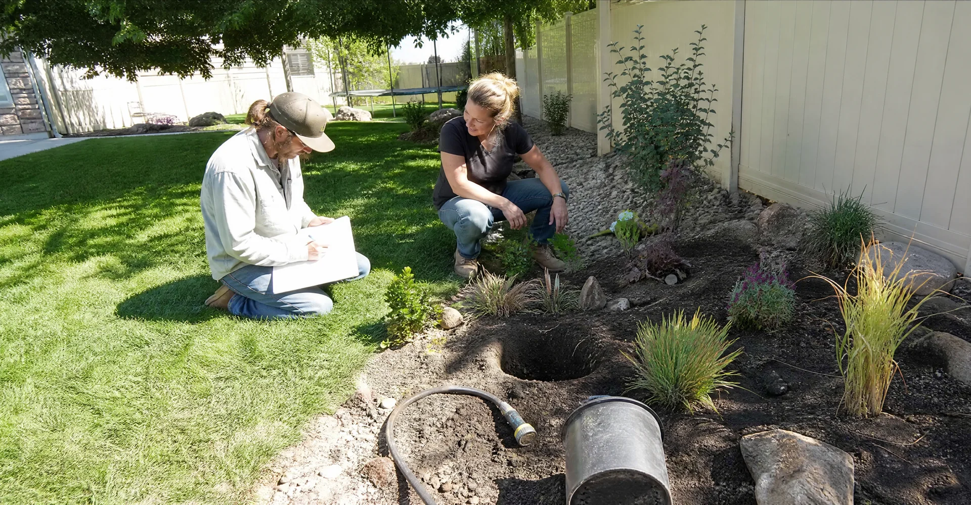 Landscape designer sketching a yard plan on site with a homeowner in Tooele County, Utah