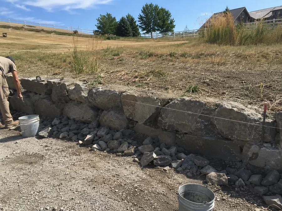 Low natural rock wall edging a driveway on a rural Tooele County property