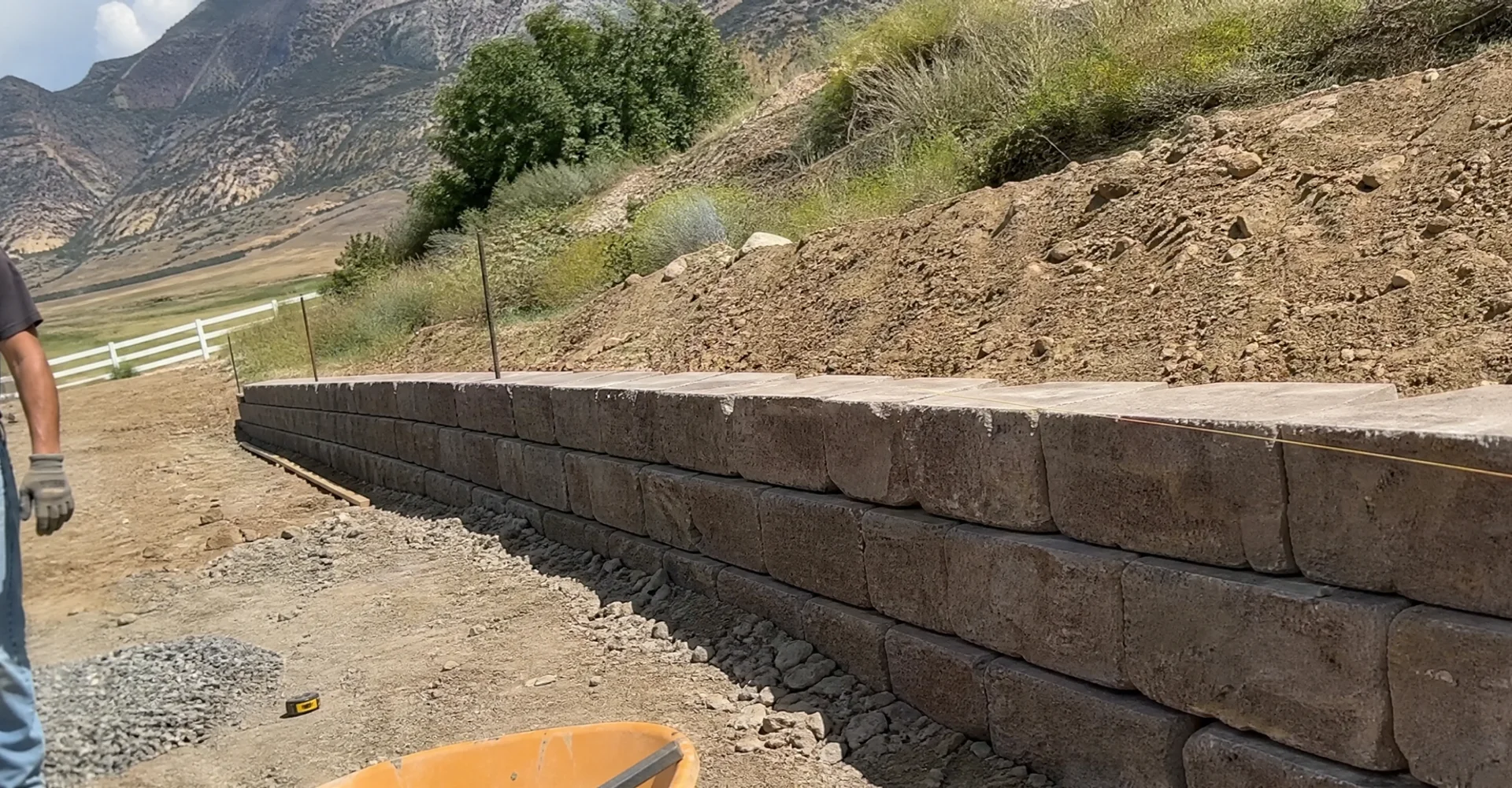 Newly built segmental block retaining wall holding a graded slope on a rural Tooele County lot