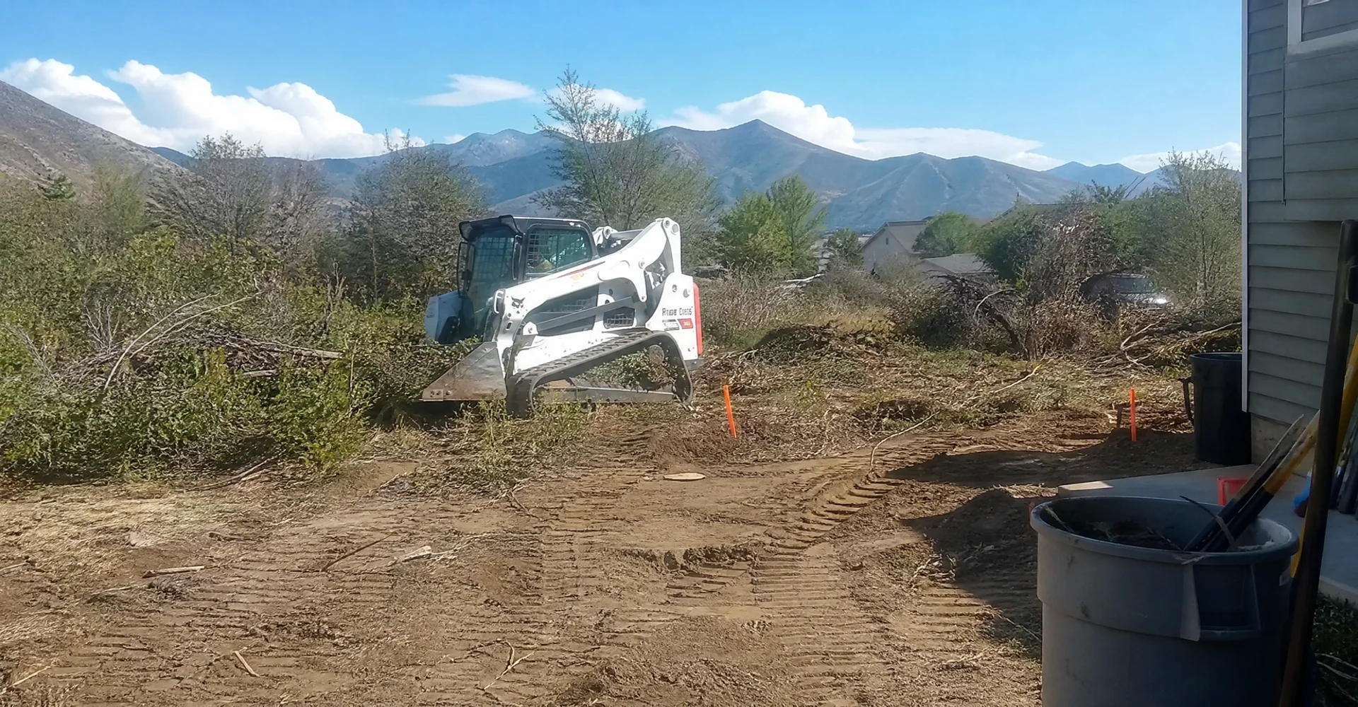 Skid steer clearing overgrown brush and vegetation on a rural Tooele County lot