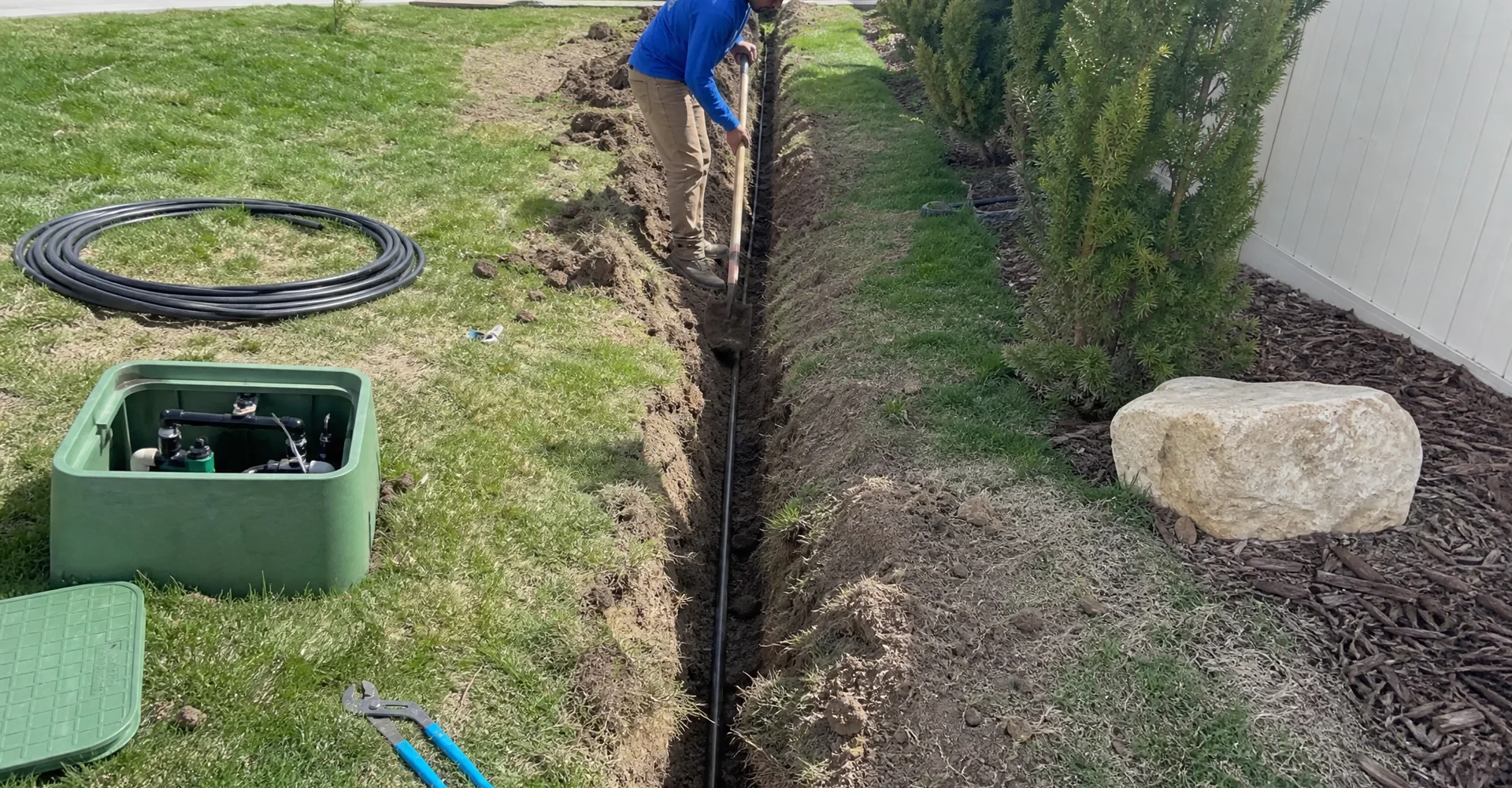 New sprinkler mainline being trenched across a Utah residential yard with the valve manifold box open
